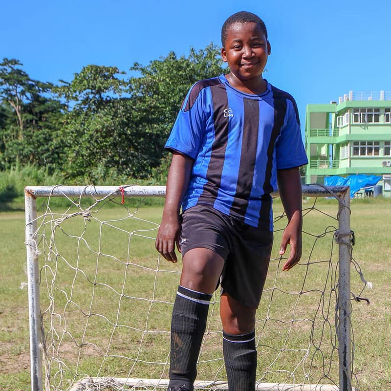 Another players standing in front of the practice goal with his right foot on the ball